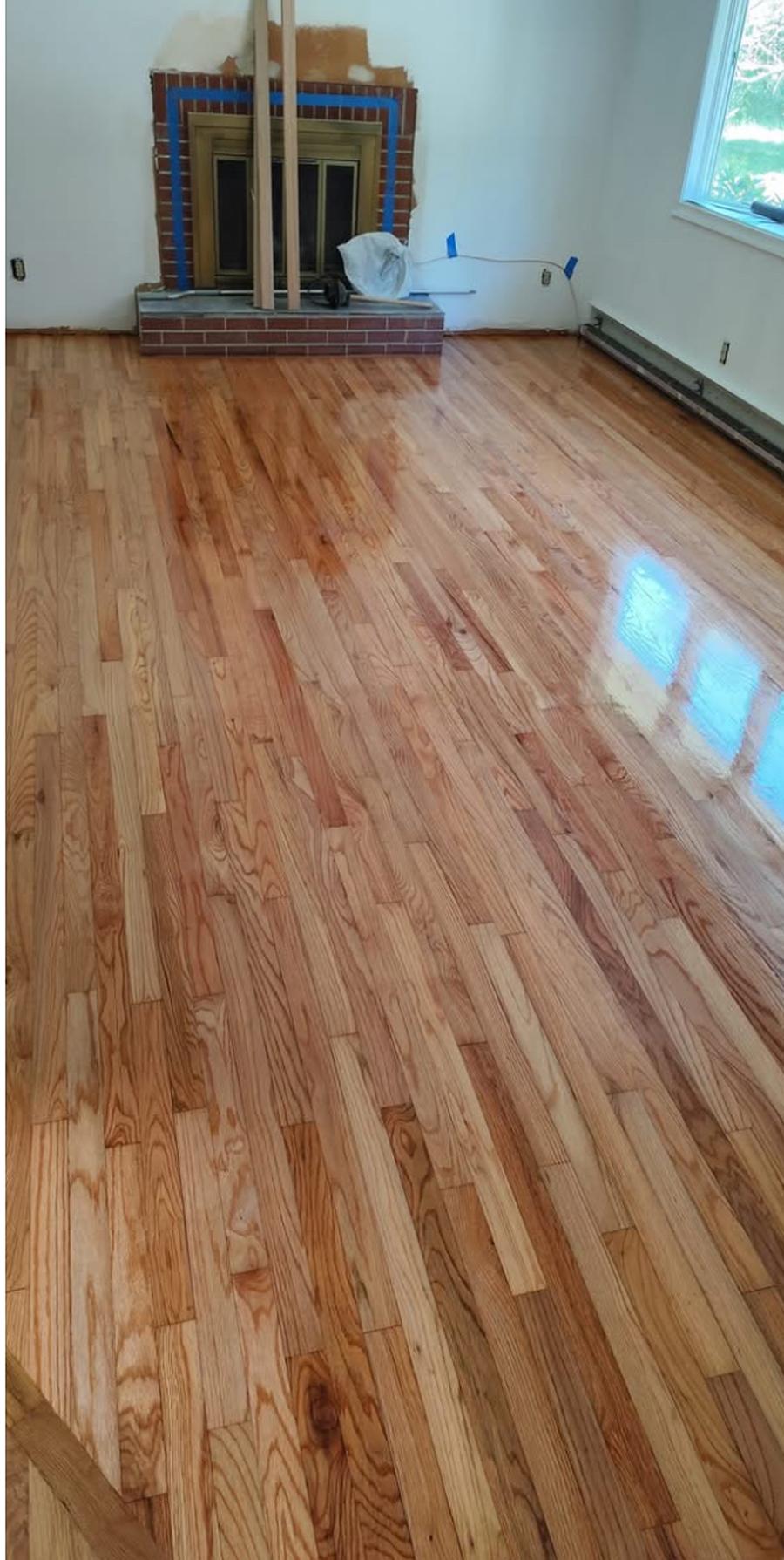 The same living room floor after sanding and refinishing, light and glossy