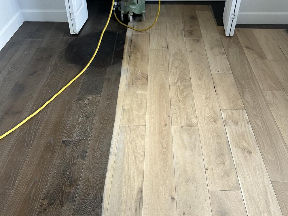 Dark finish being sanded back to bare white oak planks